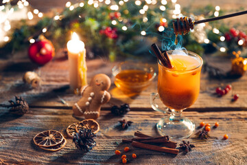 Greeting card design. Cup of hot mulled wine with cinnamon stick on Christmas decorated table. Cozy, happy home holiday atmosphere.