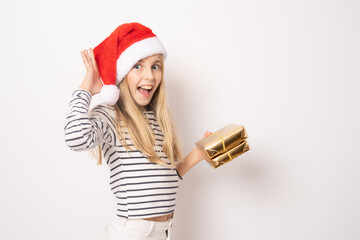 Amazed little girl in santa hat showing gift boxes isolated over white background.