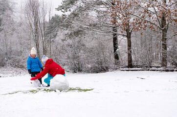 A woman and a child on a winter vacation, making a snowman cheerfully, and happy with communication.