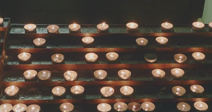 Candles lit for devotion in front of an altar in a church