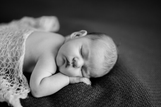 Naked baby sleeps on blanket. Portrait. Black and white photo