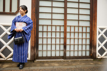 日本の屋敷の前に立つ着物を着た日本人女性