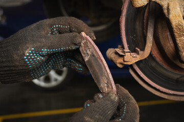 An auto mechanic shows the degree of wear of a car brake pad, close-up © Sergey Chayko
