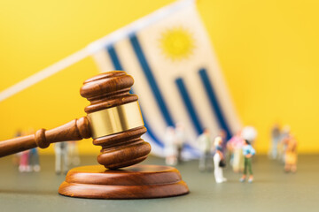 Judge gavel, Uruguayan flag and plastic toy men on colored background, concept of trials in...
