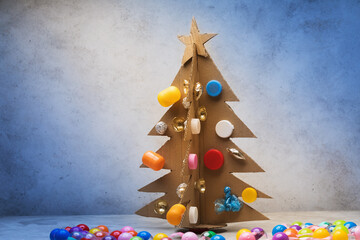 Christmas tree made of cardboard, decorated with recycled materials on an abstract background