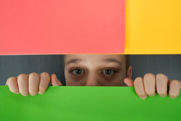 portret chłopaka ukrytego za kolorowym tłem  - obrazy, fototapety, plakaty
