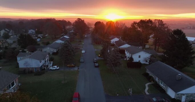 Aerial establishing shot of American homes in USA at sunrise. Peaceful beautiful calm quiet scene in America. Residential houses line street.