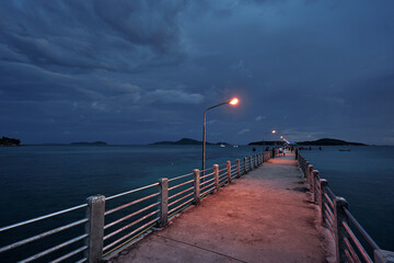 Fototapeta na wymiar Beautiful sunset landscape with sea, embankment, storm sky and pier.