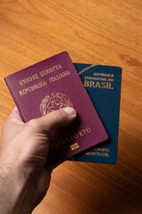 man hand holding two passports for his vacation trip, wooden background.