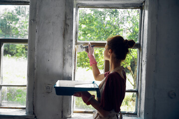 woman paints windows in the house interior room renovation