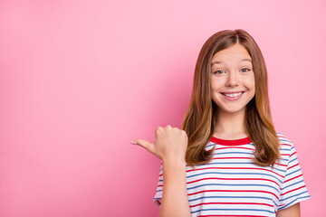 Photo of pretty little blond girl index empty space wear striped t-shirt isolated on pink color background