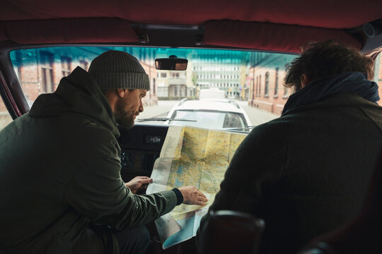 Male friends examining map while sitting in camping van during road trip
