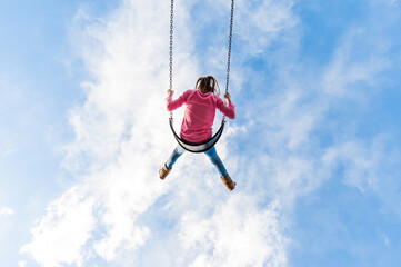 Young Girl Woman Lady on a Swing Swinging into the Blue Sky and White Clouds Childhood Unplugged Fun Pink 