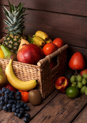 Mix of fresh juicy colorful exotic tropical fruits in basket on wooden background