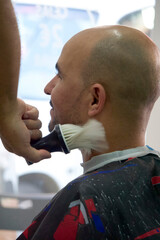 Barber cleaning his client neck with brush at barbershop.