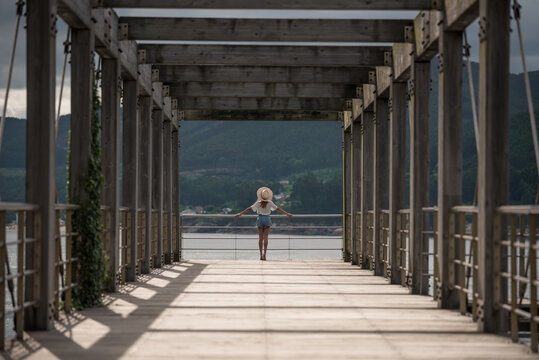 Female traveler on wooden pier near sea
