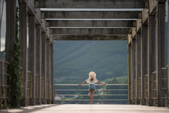Female traveler on wooden pier near sea