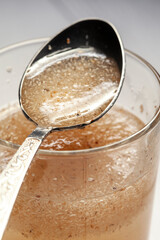 Close-up of psyllium or isabgol husk in a spoon on a glass of water, close-up, right above
