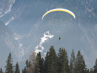 2men flying a paraglider over a valley in winter