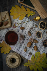 Moscow, October 2021, a cup of tea is on the notes next to books, acorns, lemon slices and autumn leaves are scattered around, still life