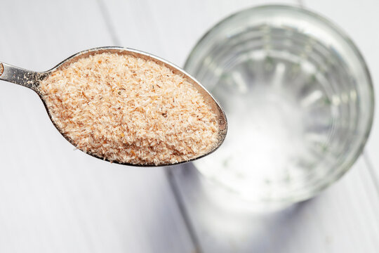 Close-up of psyllium or isabgol husk in a spoon on a glass of water, close-up, right above
