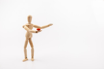 A wooden Gestalta doll or mannequin holds red and white pills in its hands on light background. The concept of choice.