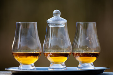 Tasting glasses of scotch whisky strong drink on old outdoor wooden table