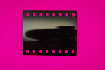 macro photo of underexposed 35mm dia filmstrip slide on pink paper background, nice photo...