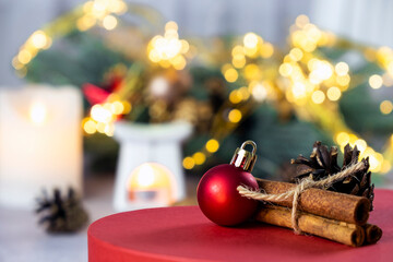 Christmas composition with red ball, cinnamon sticks and fir cone; candles, fir branch, Christmas decorations and bokeh lights. Merry Christmas and New Year greeing cards. Magic mood atmosphere.