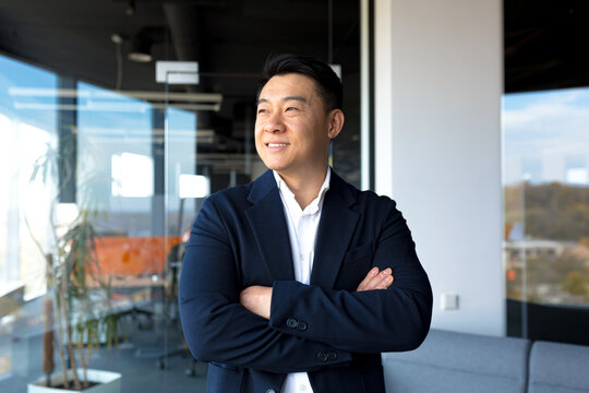 Portrait of successful business owner male boss asian cheerful happy smiling and rejoicing in modern office by big window