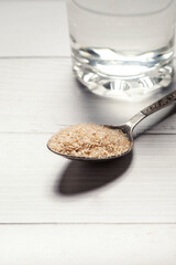 An overhead view of a transparent glass filled with water and husk of psyllium seeds, a healthy superfood
