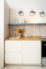 Interior light grey kitchen and red christmas decor. Preparing lunch at home on the kitchen concept. Focus on tree