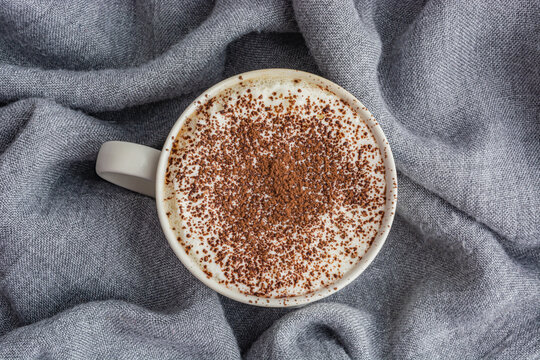 cup of coffee on gray fabric background top view close up