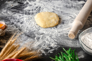 Dough, flour with accessories for the kitchen in the composition on the kitchen table