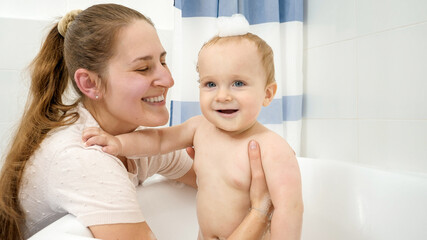 Portrait of happy smiling mother with baby boy having soap bath. Concept of children hygiene, healthcare and development at home