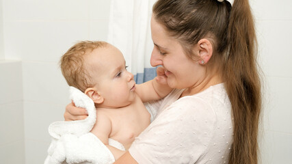 Portrait of smiling baby boy and mother after washing in bathroom at home