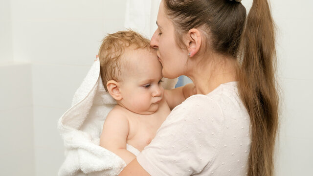 Loving mother kissing her baby son after washing in bath