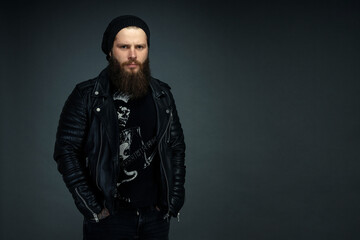 portrait of handsome bearded man in leather jacket and hat looking at the camera