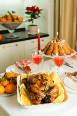 Beautifully decorated festive table with baked chicken, homemade cake, glasses of wine and candles. Baked chicken for Thanksgiving, Christmas and New Year.