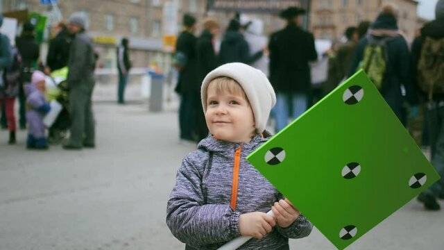 Kid with green screen empty space placard banner. Boy stand in protesting people corwd. Political rally demonstration. Child with blank place mock up poster board. Advertisement with tracking points.