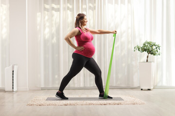 Pregnant woman exercising with a resistance band at home