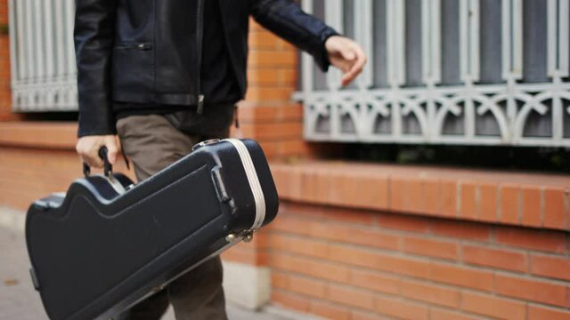 Man stroll down the street with a guitar case
