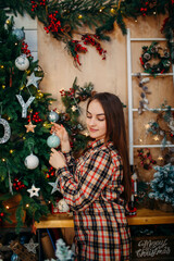 girl hanging christmas ornament on the fir