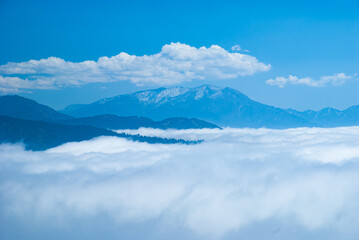 Fototapeta na wymiar Mountains covered with clouds and blue sky