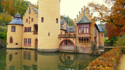 märchenhaftes  Wasserschloss im herbstlichen Spessart spiegelt seine mittelalterliche Fassade im...