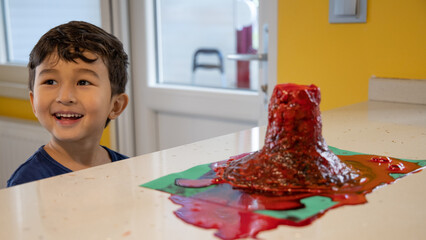 Exciting cute boy experimenting with volcano eruption