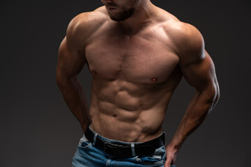 Cropped view of the beautiful and muscular caucasian man posing over the dark background. Sportive body concept