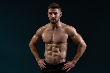 Fototapeta na wymiar Bodybuilder posing on black background. Healthy muscular caucasian man on dark background. Beautiful sporty guy male power concept