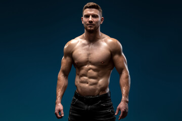 Fototapeta na wymiar Bodybuilder posing on black background. Beautiful sporty guy male power. Fitness muscled man standing at the studio