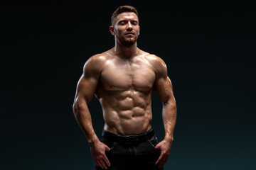 Fototapeta na wymiar Healthy muscular caucasian man on dark background. Bodybuilder posing on black background. Beautiful sporty guy male power concept